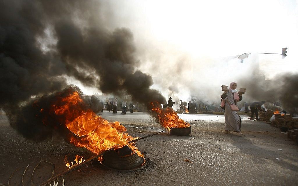 A Sudanese protester walks past burning tires as military forces tried to disperse the sit-in outside Khartoum's army headquarters on June 3, 2019. (ASHRAF SHAZLY / AFP)