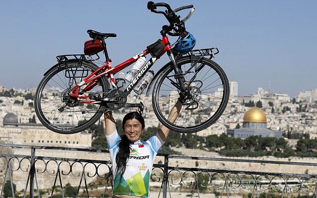 Taiwanese cyclist and world traveler Jacky Chen poses while lifting his bicycle on the Mount of Olives overlooking the Old City of Jerusalem and the Dome of the Rock on June 10, 2019. (Photo by MENAHEM KAHANA / AFP) Taiwanese cyclist and world traveler Jacky Chen poses while lifting his bicycle on the Mount of Olives overlooking the Old City of Jerusalem and the Dome of the Rock on June 10, 2019. (Photo by MENAHEM KAHANA / AFP)