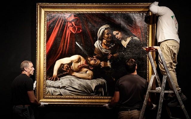 Workers hang on a wall a painting believed by some experts to be Caravaggio's 'Judith Beheading Holofernes' for its public presentation at the Drouot auction house in Paris on June 14, 2019 before it goes under the hammer on June 27 in Toulouse, the city where it was discovered five years ago. (Francois Guillot/AFP) Workers hang on a wall a painting believed by some experts to be Caravaggio's 'Judith Beheading Holofernes' for its public presentation at the Drouot auction house in Paris on June 14, 2019 before it goes under the hammer on June 27 in Toulouse, the city where it was discovered five years ago. (Francois Guillot/AFP)