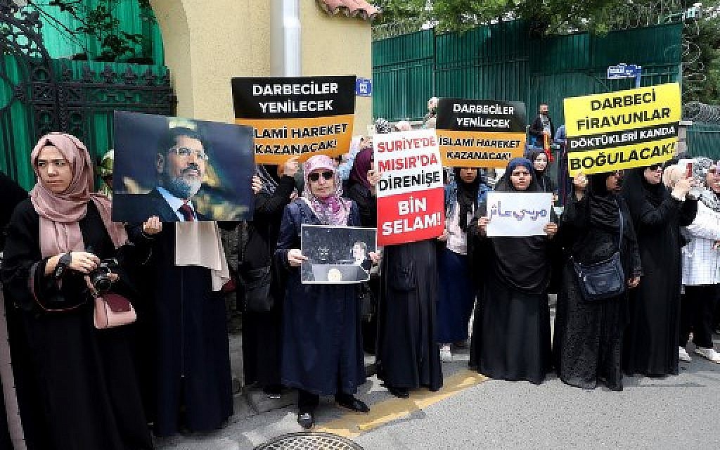 A group of women holds  banner reads " The putschists will be defeated, Islamic movement will win " and " Thousand greetings to the resistance in Syria and Egypt " during a symbolic funeral prayer for the Egyptian President Mohamed Morsi on June 18, 2019 in front of the embassy in Ankara. (Adem ALTAN / AFP)