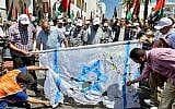 Protesters tear at a makeshift Israeli flag during a protest in the Moroccan capital Rabat on June 23, 2019, against the US-led economic conference in Bahrain with its declared aim of achieving Palestinian prosperity. (AFP)