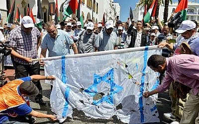 Protesters tear at a makeshift Israeli flag during a protest in the Moroccan capital Rabat on June 23, 2019, against the US-led economic conference in Bahrain with its declared aim of achieving Palestinian prosperity. (AFP)