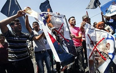 Palestinian demonstrators chant slogans behind defaced posters of Israeli Prime Minister Benjamin Netanyahu and US President Donald Trump during a protest against a US-sponsored Middle East economic conference in Bahrain, on June 26, 2019, in Khan Younis in the southern Gaza Strip. (SAID KHATIB / AFP)