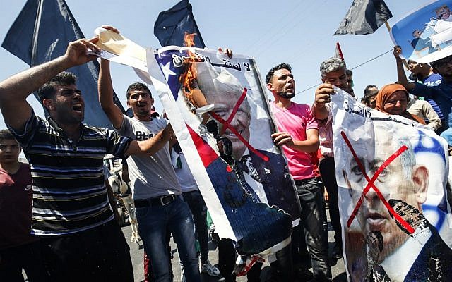 Palestinian demonstrators chant slogans behind defaced posters of Israeli Prime Minister Benjamin Netanyahu and US President Donald Trump during a protest against a US-sponsored Middle East economic conference in Bahrain, on June 26, 2019, in Khan Younis in the southern Gaza Strip. (SAID KHATIB / AFP) Palestinian demonstrators chant slogans behind defaced posters of Israeli Prime Minister Benjamin Netanyahu and US President Donald Trump during a protest against a US-sponsored Middle East economic conference in Bahrain, on June 26, 2019, in Khan Younis in the southern Gaza Strip. (SAID KHATIB / AFP)