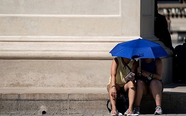 People use an umbrella to shelter from the sun near the Louvre Pyramid (Pyramide du Louvre) during a heatwave in Paris on June 26, 2019. (Kenzo TRIBOUILLARD / AFP)
