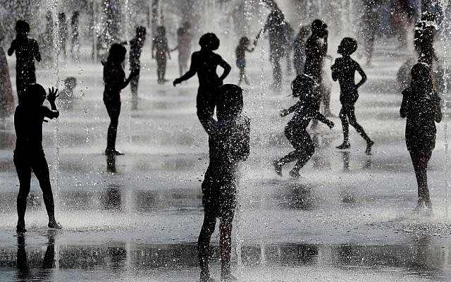 Children play under water jets in a fountain as they cool off during a heatwave in Nice, France on June 26, 2019. (VALERY HACHE / AFP) Children play under water jets in a fountain as they cool off during a heatwave in Nice, France on June 26, 2019. (VALERY HACHE / AFP)