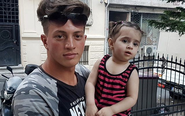 Algerian citizen Fawzi Zabaat (L), 17, poses with Syrian toddler Doha Muhammed he caught as she was falling from the second floor at Fatih district in Istanbul on June 27, 2019. (STR / DHA / AFP)
