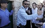 An Israeli policeman prevents ultra-Orthodox Jewish men from entering the Tomb of the Kings site owned and administered by the French Consulate of Jerusalem because they did not pre-register their visit through the internet which they do not use for religious reasons, in East Jerusalem on June 27 2019. (Photo by MENAHEM KAHANA / AFP)