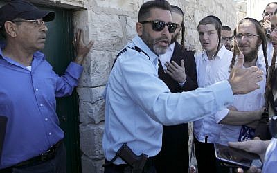 An Israeli policeman prevents ultra-Orthodox Jewish men from entering the Tomb of the Kings site owned and administered by the French Consulate of Jerusalem because they did not pre-register their visit through the internet which they do not use for religious reasons, in East Jerusalem on June 27 2019. (Photo by MENAHEM KAHANA / AFP)