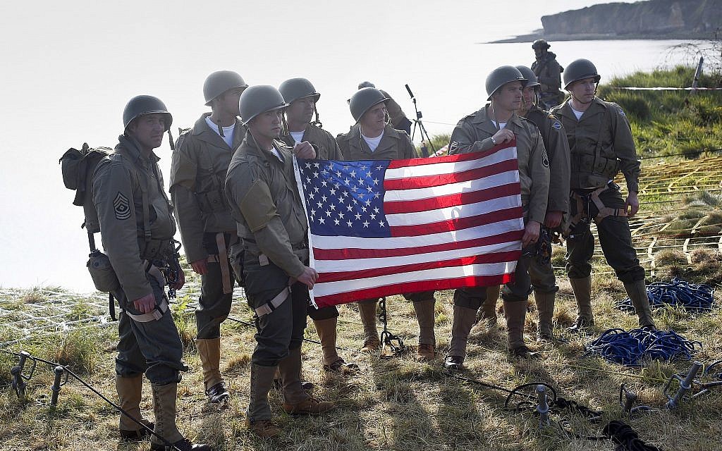 Rangers from the US 75th Ranger Regiment, in period dress, hold the American flag after scaling the cliffs of Pointe-du-Hoc in Cricqueville-en-Bessin, Normandy, France, on June 5, 2019. During the American assault of Omaha and Utah beaches on June 6, 1944, US Army Rangers scaled the 100-foot cliffs to seize German artillery pieces that could have fired on the American landing troops. (AP Photo/Thibault Camus)