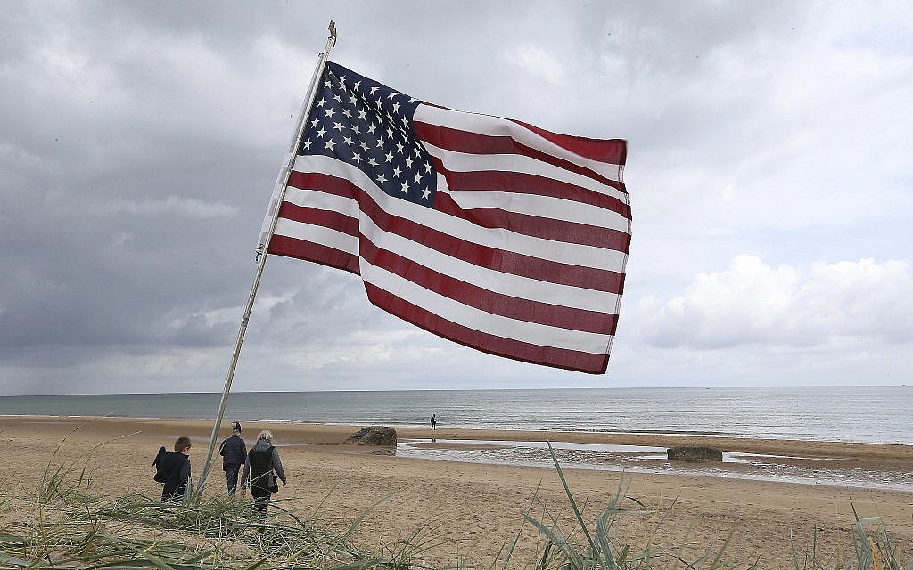 People walk on Omaha Beach, Normandy, where an American flag is planted, on June 5, 2019. Extensive commemorations are being held in the UK and France to honor the nearly 160,000 troops from Britain, the United States, Canada and other nations who landed in Normandy on June 6, 1944 in history's biggest amphibious invasion. (AP Photo/David Vincent)