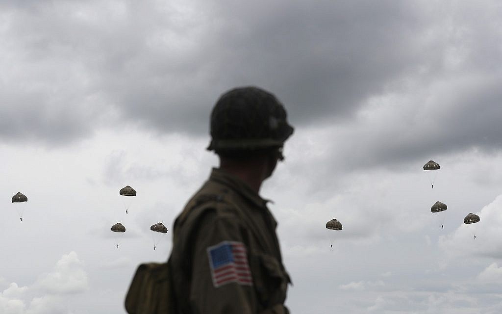 A WWII enthusiast watches French and British parachutists jumping during a commemorative parachute jump over Sannerville, Normandy, June 5, 2019. Extensive commemorations are being held in the UK and France to honor the nearly 160,000 troops from Britain, the United States, Canada and other nations who landed in Normandy on June 6, 1944 in history's biggest amphibious invasion. (AP Photo/Thibault Camus)