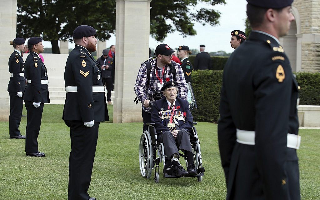 Canadian World War II veteran Jim Warford, center, arrives for a ceremony at the Beny-sur-Mer Canadian War Cemetery in Reviers, Normandy, France, June 5, 2019. The cemetery contains 2,049 headstones marking the dead of the 3rd Division and graves of 15 airmen who died on D-Day in World War II. (AP Photo/David Vincent)