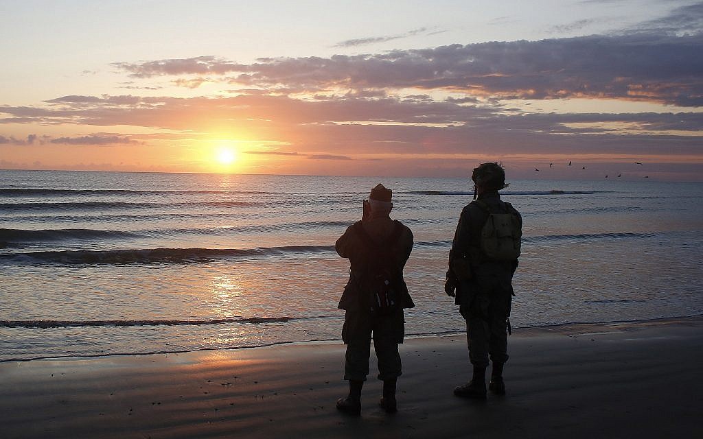 World War II reenactors stand looking out to sea on Omaha Beach, in Normandy, France, at dawn on June 6, 2019 during commemorations of the 75th anniversary of D-Day. (AP Photo/Thibault Camus)