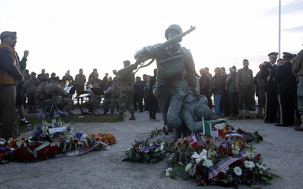 Floral tributes are placed at the National Guard Monument Memorial as members of the USAREUR band play in the background near Omaha Beach, in Normandy, France, June 6, 2019 during commemorations of the 75th anniversary of D-Day. (AP Photo/Thibault Camus)