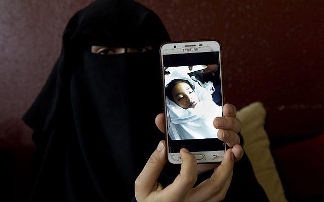 In this May 27, 2019 photo, Muna Awad, mother of 5-year-old Aisha al-Loulu, shows a photo of her daughter while in a Jerusalem hospital, at the family home in the Bureij refugee camp in the central Gaza Strip. (AP Photo/Hatem Moussa) In this May 27, 2019 photo, Muna Awad, mother of 5-year-old Aisha al-Loulu, shows a photo of her daughter while in a Jerusalem hospital, at the family home in the Bureij refugee camp in the central Gaza Strip. (AP Photo/Hatem Moussa)