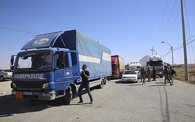 Trucks laden with aid for displaced Syrians wait to cross from Jordan to the Syrian side of the border, in Jabir As Sirhan, Jordan, July 1, 2018. (AP Photo/Omar Akour)