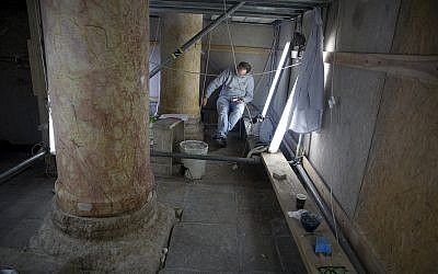 In this Thursday, Dec. 6, 2018 photo, a restoration expert works on a granite column inside the Church of the Nativity, built atop the site where Christians believe Jesus Christ was born, in the West Bank City of Bethlehem. (AP/Majdi Mohammed)