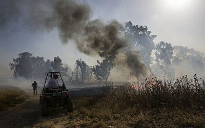 Illustrative: An Israeli firefighter battles a fire started by an incendiary device launched from the Gaza Strip, near the Gaza border fence, May 15, 2019. (AP/Tsafrir Abayov)