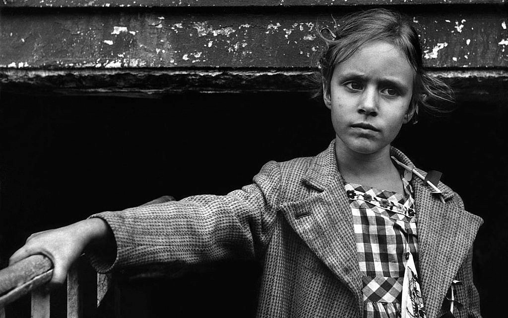 Detail of a pre-teen girl wearing a gingham dress and wide lapel tweed coat with her hand on a railing, New York, 1957. (Harold Feinstein/Courtesy)