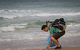 Israeli blogger Gil Drori picked up a plastic bag on the Beit Yanai beach on November 23, 2018, during his 9-day journey to raise awareness of the harmful effects of disposable plastic pollution on the Mediterranean Sea. (Meir Vaknin/Flash90)