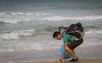 Israeli blogger Gil Drori picked up a plastic bag on the Beit Yanai beach on November 23, 2018, during his 9-day journey to raise awareness of the harmful effects of disposable plastic pollution on the Mediterranean Sea. (Meir Vaknin/Flash90)