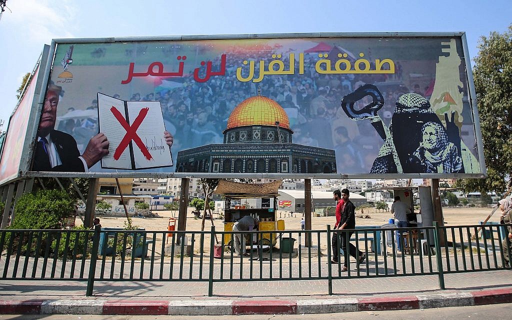 Palestinians walk under a giant billboard against US President Donald Trump's “Deal Of The Century”, in Gaza City on June 17, 2019. (Hassan Jedi/Flash90)