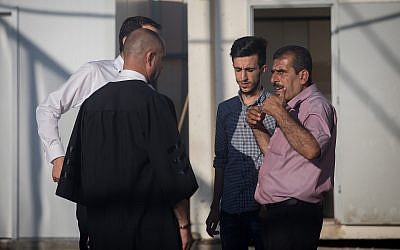 Attorney Nashaf Darwish (L) speaks with the brother and son of Mahmoud Qadusa, a Palestinian man charged with kidnapping and raping a 7-year-old Israeli girl, at the Judea Military Court in the West Bank on June 19, 2019. (Yonatan Sindel/Flash90)