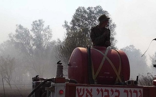 IDF soldiers help firefighters battle brushfires near the Gaza border started by an incendiary device launched from the Gaza Strip, on June 24, 2019. (Yankele Grossfeld/Sha'ar Hanegev Regional Council)