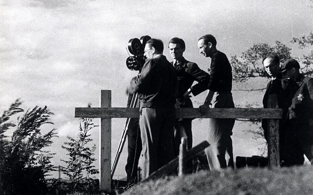 A film crew takes motion pictures in the Theresienstadt ghetto during the filming of a Nazi propaganda film in 1944. A Jewish assistant wearing a Star of David is on the right. (Public domain)