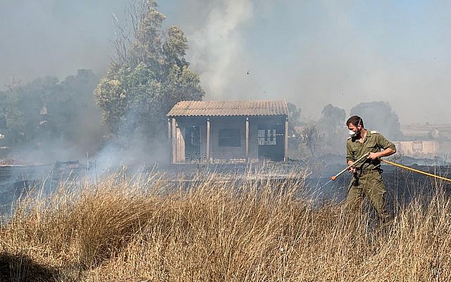 A military firefighter works to extinguish a blaze caused by an incendiary device from the Gaza Strip in a field in the Sha'ar Hanegev region of southern Israel on June 27, 2019. (Sha'ar Hanegev regional council)