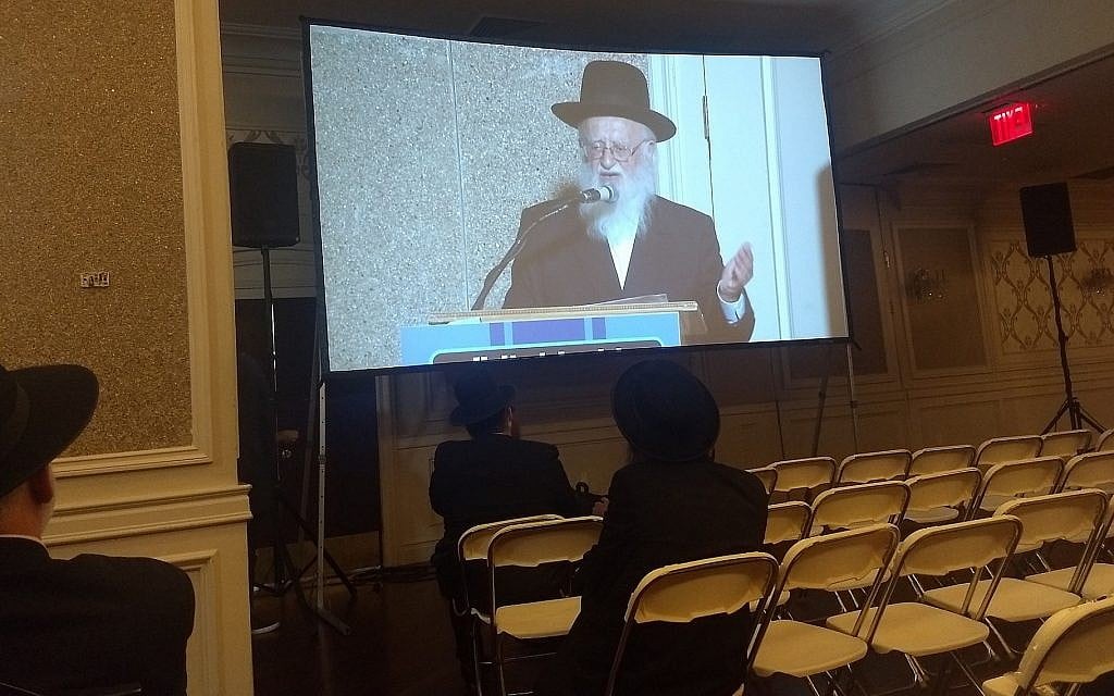 Rabbi Hillel Handler, an Orthodox anti-vaccination leader, speaks via projection screen to an anti-vaccination rally in Brooklyn at a Jewish wedding hall, June 4, 2019. (Ben Sales/JTA) Rabbi Hillel Handler, an Orthodox anti-vaccination leader, speaks via projection screen to an anti-vaccination rally in Brooklyn at a Jewish wedding hall, June 4, 2019. (Ben Sales/JTA)