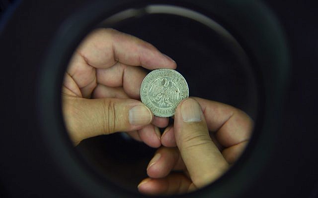 A Hungarian archaeologist, Ferenc Redo, examines a metal coin from a Holocaust victim's collection in the Balatoni Museum in the town of Keszthely, 200 kilometers west of Budapest, Hungary on May 22, 2019. (Attila Kisbenedek/AFP) A Hungarian archaeologist, Ferenc Redo, examines a metal coin from a Holocaust victim's collection in the Balatoni Museum in the town of Keszthely, 200 kilometers west of Budapest, Hungary on May 22, 2019. (Attila Kisbenedek/AFP)