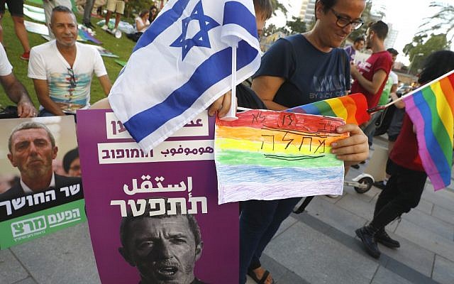 Members of the LGBT community hold a banner reading in Hebrew "A Homophobic Racist Has to Quit" during a rally against Education Minister Rafi Peretz in Tel Aviv on July 14, 2019. (Photo by JACK GUEZ / AFP) Members of the LGBT community hold a banner reading in Hebrew "A Homophobic Racist Has to Quit" during a rally against Education Minister Rafi Peretz in Tel Aviv on July 14, 2019. (Photo by JACK GUEZ / AFP)