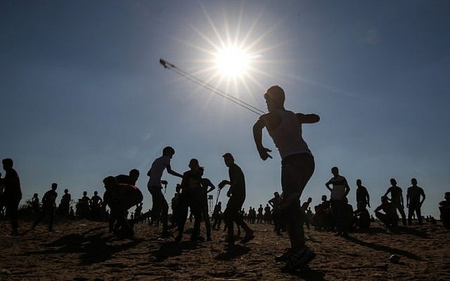 A young Palestinian uses a slingshot to hurl rocks at Israeli troops during clashes between Palestinian protesters and Israeli forces across the barbed-wire fence during a border demonstration near Rafah in the southern Gaza Strip on July 19, 2019. (Said Khatib/AFP) A young Palestinian uses a slingshot to hurl rocks at Israeli troops during clashes between Palestinian protesters and Israeli forces across the barbed-wire fence during a border demonstration near Rafah in the southern Gaza Strip on July 19, 2019. (Said Khatib/AFP)