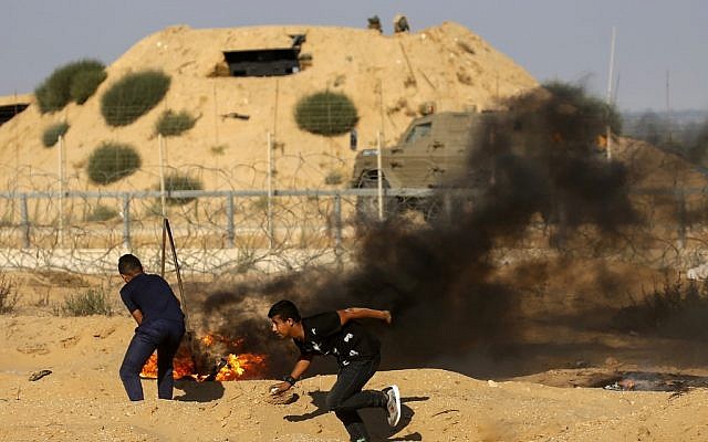 Illustrative: Palestinian protesters burn tires during clashes with Israeli forces across the border fence with Israel near Rafah in the southern Gaza Strip on July 19, 2019. (Said KHATIB/AFP) Illustrative: Palestinian protesters burn tires during clashes with Israeli forces across the border fence with Israel near Rafah in the southern Gaza Strip on July 19, 2019. (Said KHATIB/AFP)