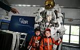 Young attendees stand by a space suit during the Apollo 11, 50th anniversary celebration at Space Center Houston on July 20, 2019, in Houston, Texas. (Loren ELLIOTT / AFP)