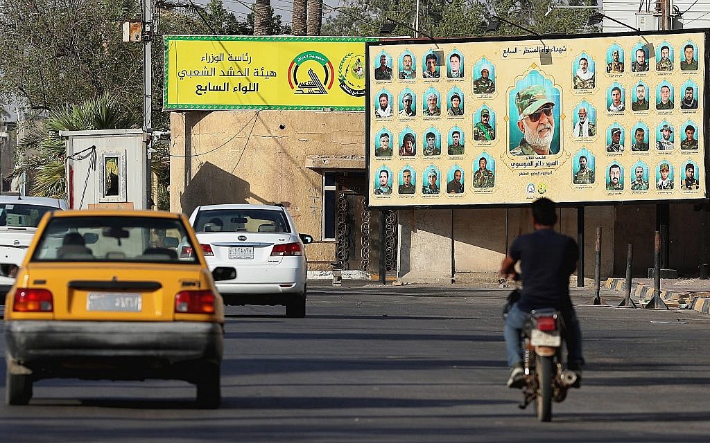 In this July 2, 2019 photo, motorists pass by a Popular Mobilization poster of volunteer militants who were killed in Iraq fighting Islamic State militants in Basra, Iraq. (AP Photo/Nabil al-Jurani)