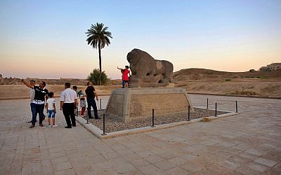 People stand near the Lion of Babylon at the archaeological site of Babylon, Iraq, Friday, July 5, 2019.. (AP Photo/Anmar Khalil)