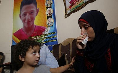 Raeda, mother of 14-year-old Mohammed Ayyoub, sits near a poster with his photo, at the family home in Jabaliya refugee camp, July 2, 2019. Mohammed was killed during a protest on the fence separating Israel and Gaza in 2018. (AP Photo/Hatem Moussa)