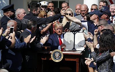 US President Donald Trump holds up the signed H.R. 1327 bill in the Rose Garden of the White House on July 29, 2019, in Washington. (AP/Alex Brandon)