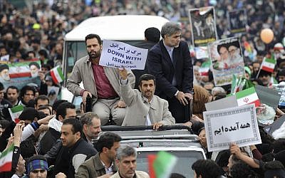 Escorted by his bodyguards, Iranian President Mahmoud Ahmadinejad, holds an anti-Israel placard, from his car, as he attends a rally marking the 32nd anniversary of the 1979 Islamic Revolution, at the Azadi (Freedom) Square in Tehran, Iran, Friday, Feb. 11, 2011. (AP Photo/Vahid Salemi)