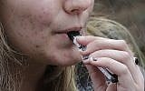 A high school student uses a vaping device near a school campus in Cambridge, Massachusetts, April 11, 2018. (AP Photo/Steven Senne, File)