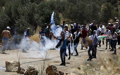 Palestinian protesters throw back a tear gas canister fired by Israeli troops during a protest near the West Bank city of Nablus, June 28, 2019 (AP Photo/Majdi Mohammed)