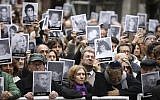 People hold up pictures of people who died during the bombing at the AMIA Jewish center that killed 85 people, on the 25th anniversary of the attack in Buenos Aires, Argentina, July 18, 2019. (AP Photo/Natacha Pisarenko)