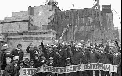 Workers who constructed the base for a cement sarcophagus to cover Chernobyl's exploded reactor four pose, in front of the still-exposed destroyed reactor building, with a poster reading: 'We carried out the mission ordered by the government.' (AP Photo/ Volodymyr Repik)