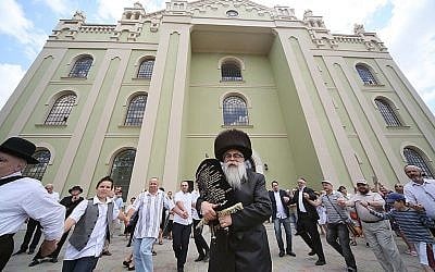 Yaakov Dov Bleich carrying a Torah scroll into the synagogue of Drohobycz, Ukraine on July 3, 2019. (Rephael Isaak Vilenskiy via JTA)