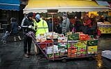 Workers check their phones while collecting trash at Mahane Yehuda market, in Jerusalem,
January 02, 2018 (Abbi Berkovitz/FLASH90)