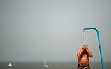 A man cools off in a beach shower during a hot summer day at the beach in De Haan, Belgium, July 25, 2019. (AP Photo/Francisco Seco)