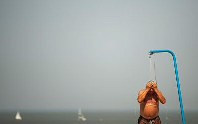 A man cools off in a beach shower during a hot summer day at the beach in De Haan, Belgium, July 25, 2019. (AP Photo/Francisco Seco)